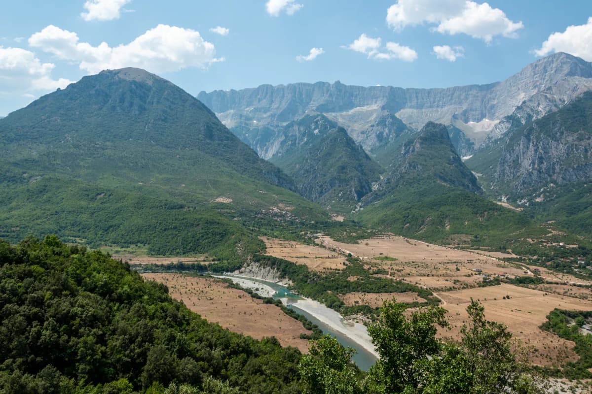 Aerial view of Përmet valley with lush greenery and majestic mountains in Albania.