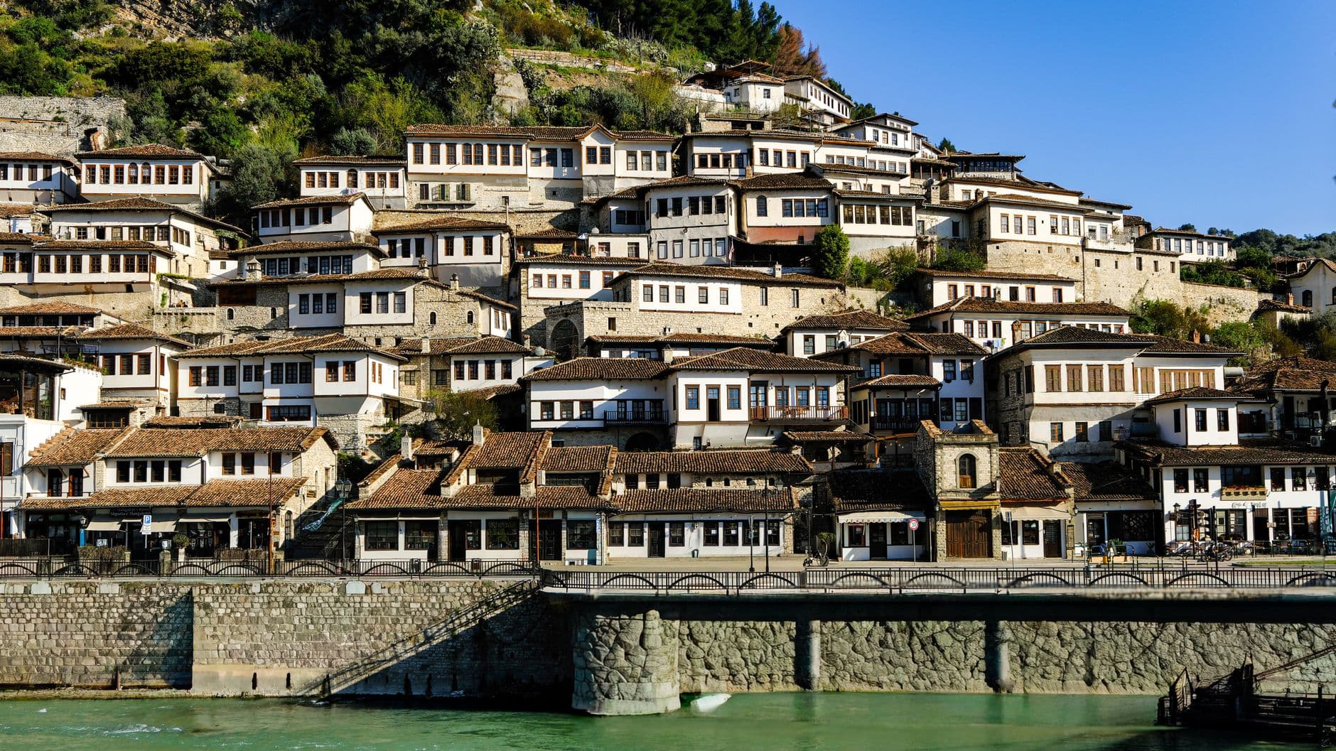Les façades blanches et les rangées de fenêtres du quartier Mangalem de Berat, étagées sous la citadelle