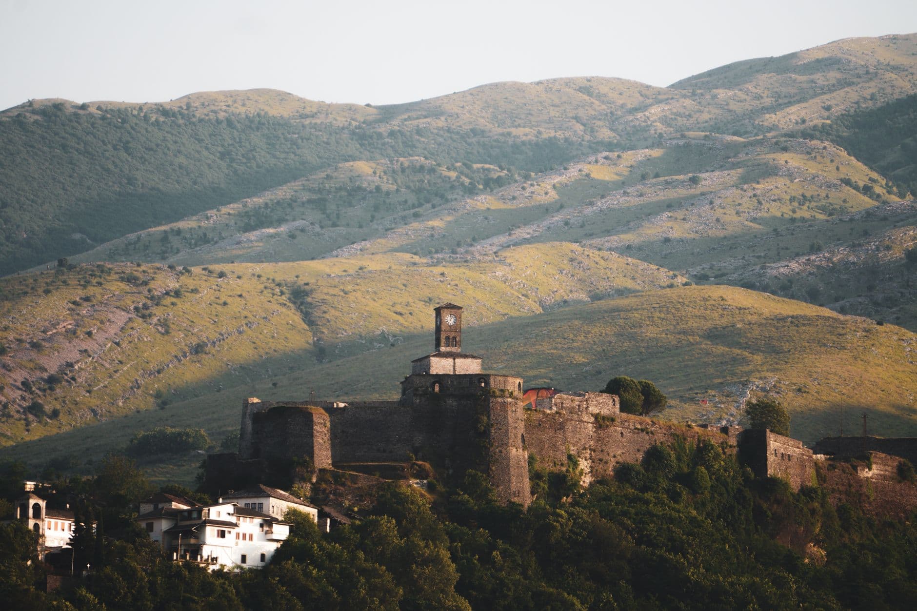 Les toits de lauzes grises des maisons-tours de Gjirokastër étagés sous la citadelle, face à la vallée du Drino
