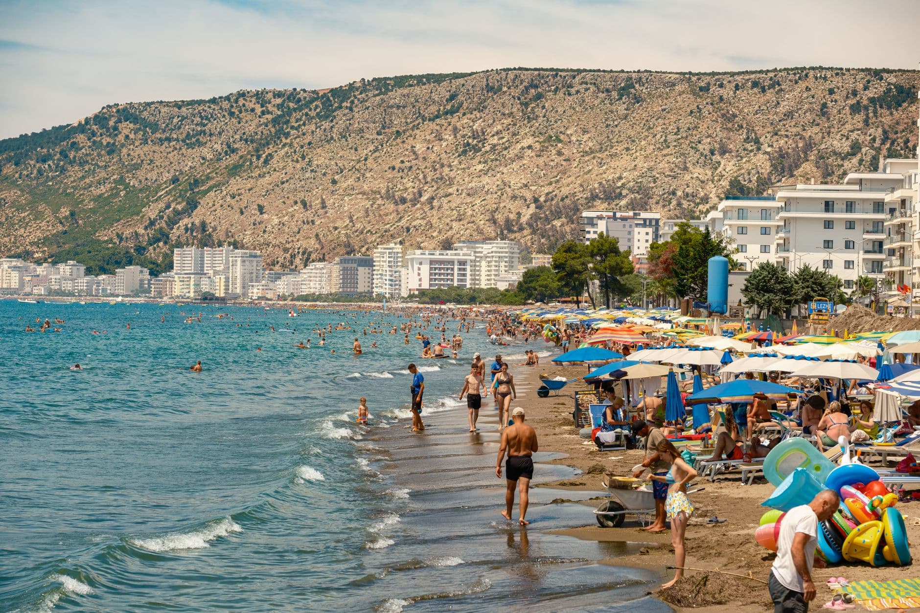 La baie de Sarandë en arc de cercle, immeubles blancs étagés sur les pentes et front de mer bordant la mer Ionienne