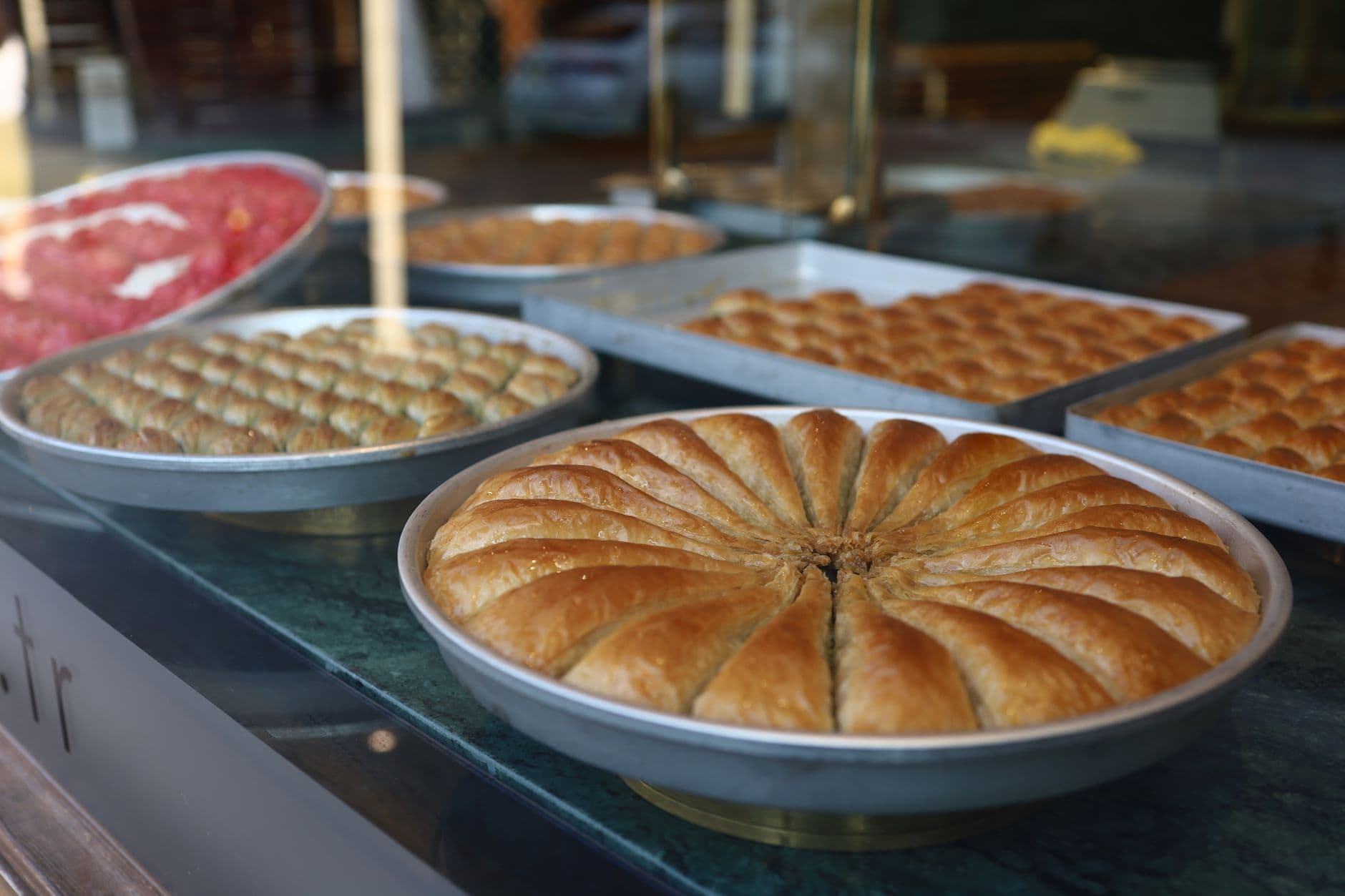 Table couverte de plats albanais : tourte feuilletée dorée, gratin au yaourt, poivrons farcis, fromage blanc et salade de tomates