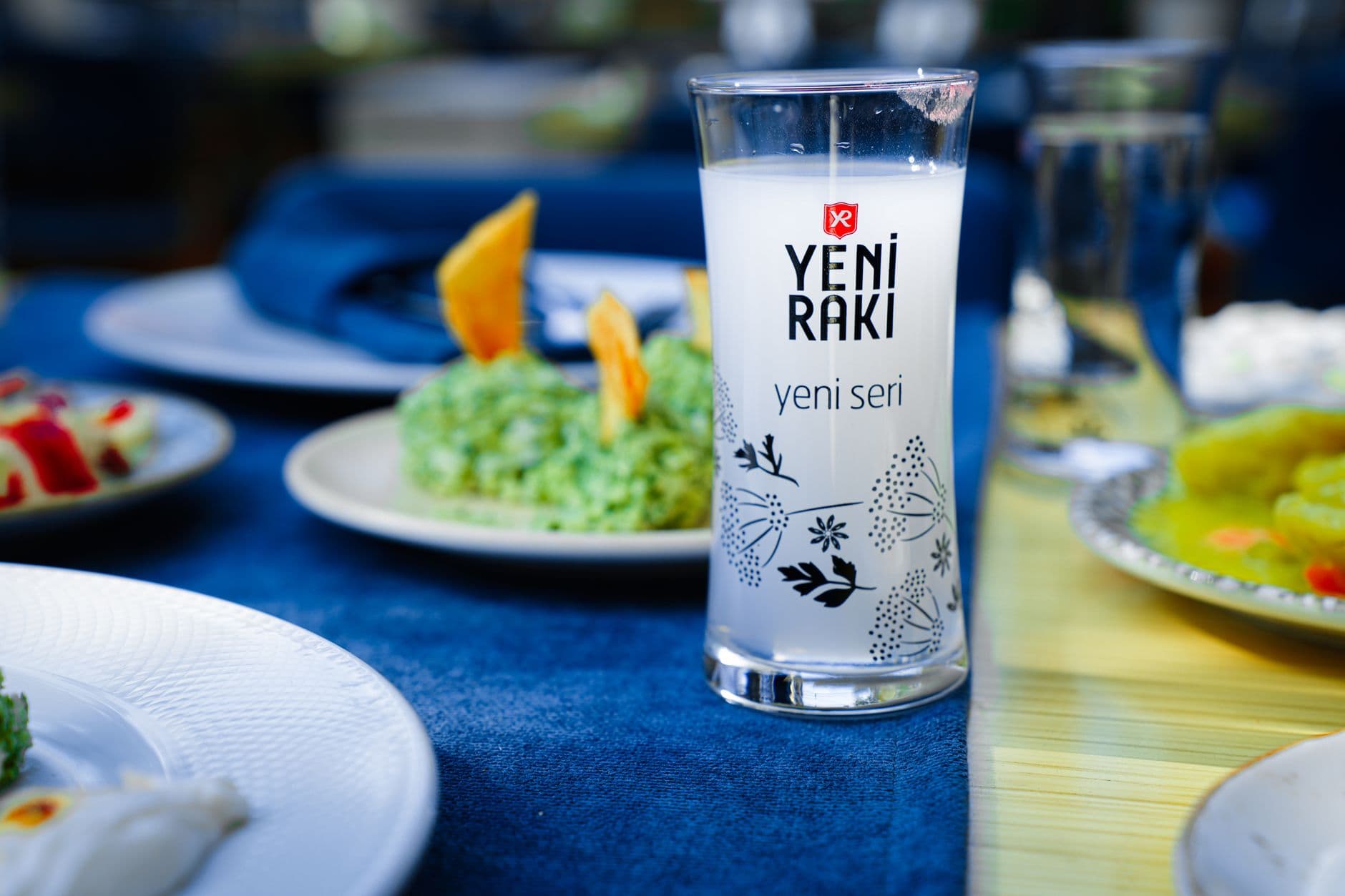 Petits verres d'eau-de-vie transparente et bouteille de vin rouge posés sur une table en bois avec des grappes de raisin