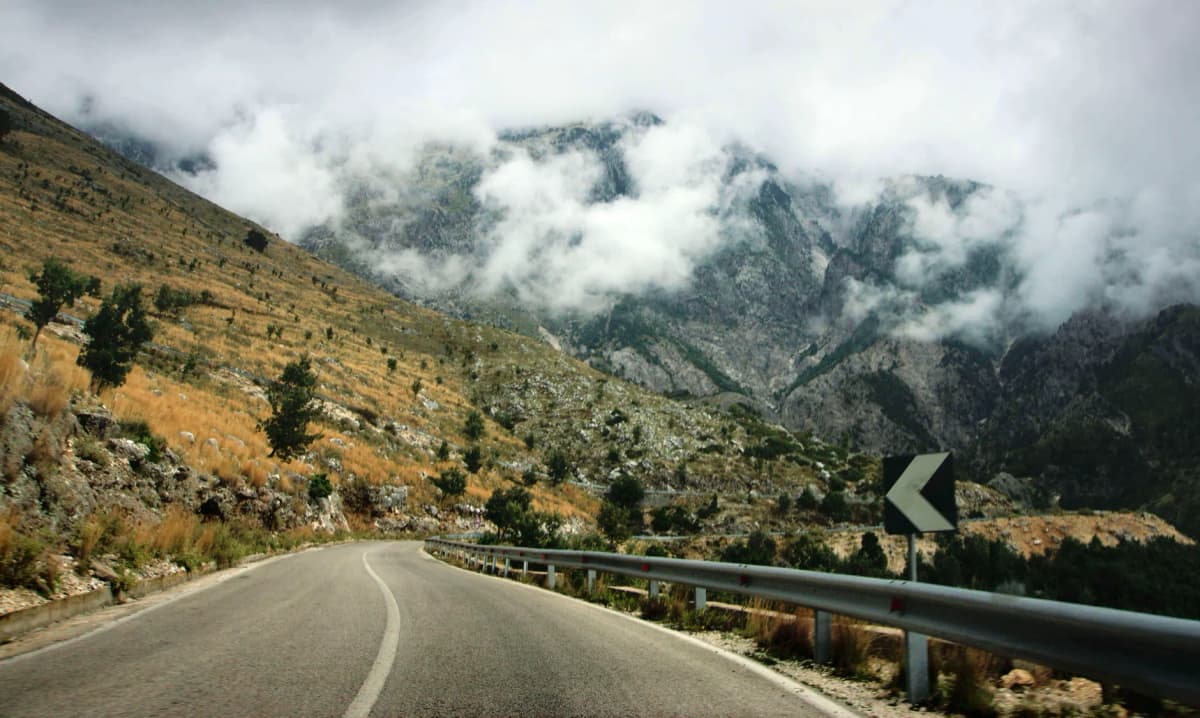 Curvy road through misty mountains in Vlorë County, Albania. Ideal for travel imagery.